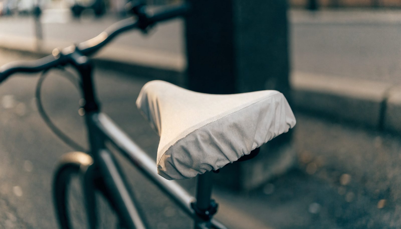 Stadtfahrrad mit einem schlichten Stoff-Sattelbezug an einer Straße in gedeckten Grautönen